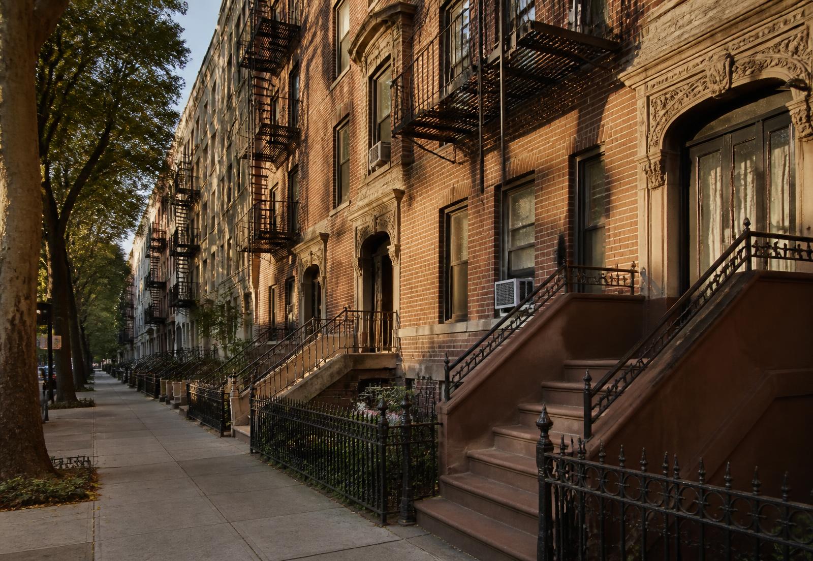 Bronx residential street lined with prewar brick apartment buildings and brownstone stoops